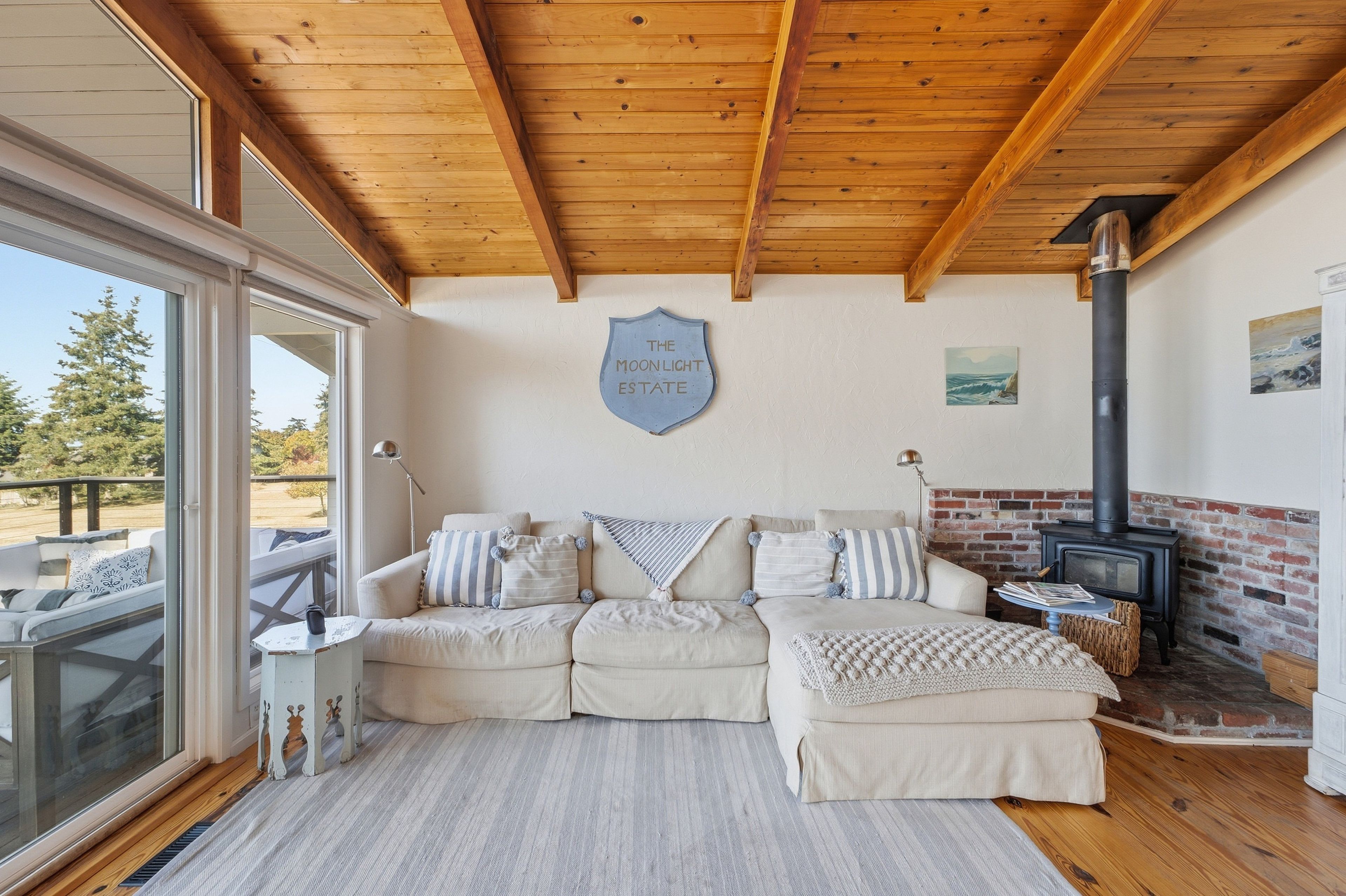 A cozy living room with a wooden ceiling, a sofa set, a fireplace, and a sign reading 'The Moonlight Estate.'