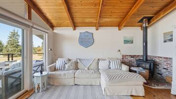A cozy living room with a wooden ceiling, a sofa set, a fireplace, and a sign reading 'The Moonlight Estate.'
