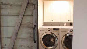 Un cuarto de lavandería con dos lavadoras y una puerta de madera.