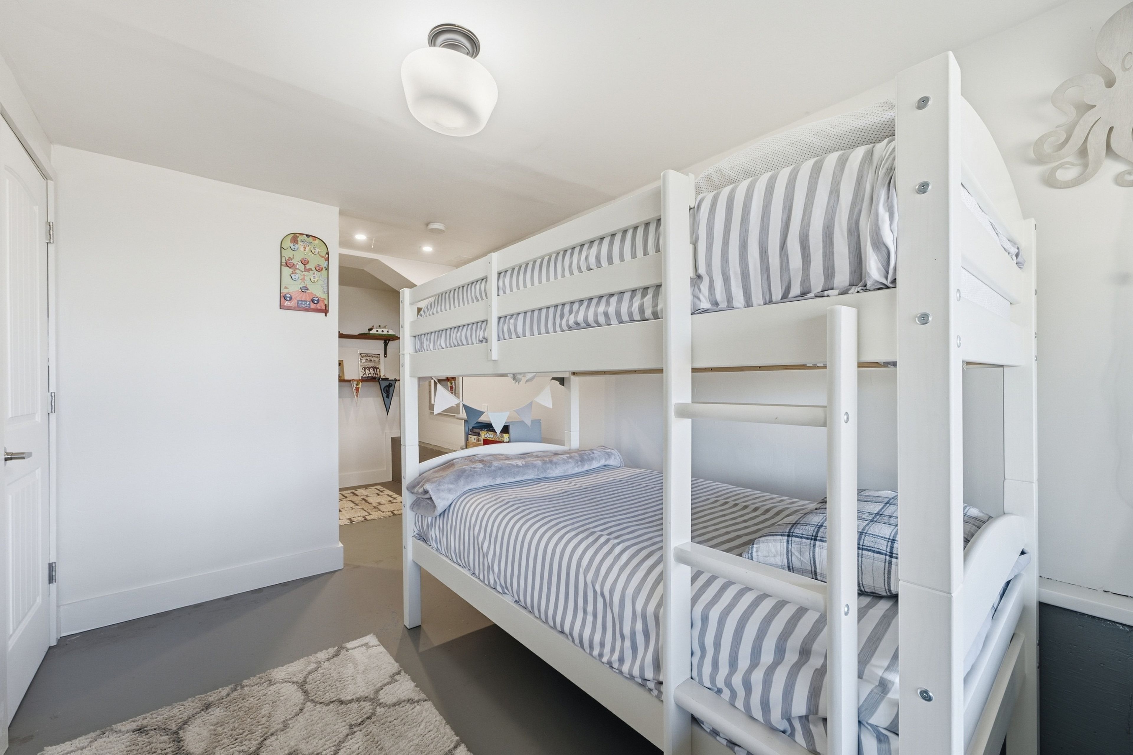 Een slaapkamer met stapelbedden, een wit plafond en een kleed op de vloer.