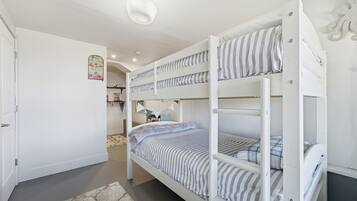 Een slaapkamer met stapelbedden, een wit plafond en een kleed op de vloer.