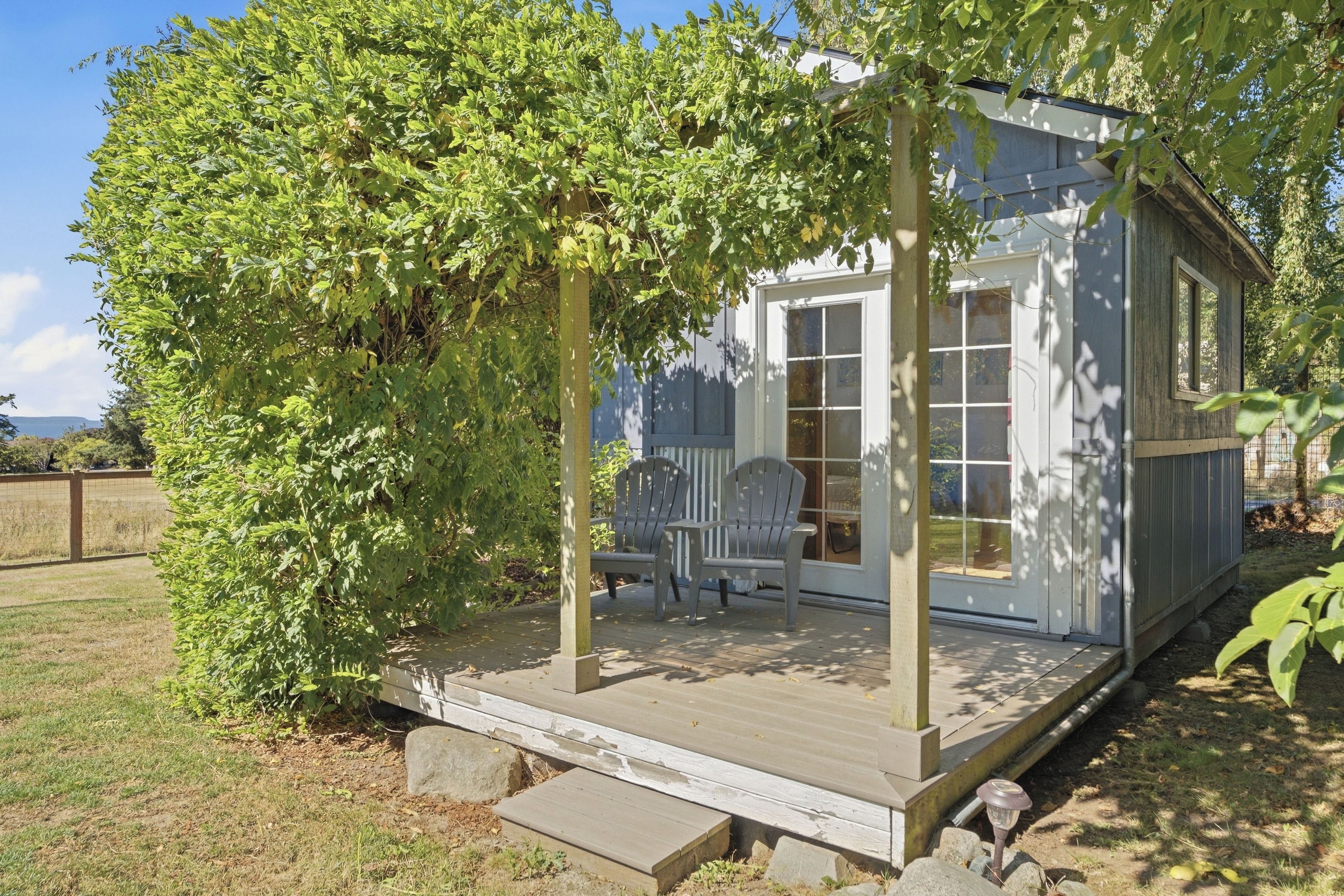 A wooden deck with a covered seating area and a small shed.
