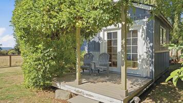A wooden deck with a covered seating area and a small shed.