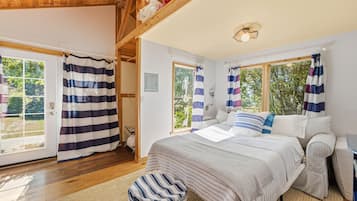 A bedroom with a bed, a window, curtains, and a wooden ceiling.