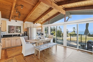 Eine moderne Küche mit Holzausstattung, einem Essbereich mit einer Bank und großen Fenstern mit Blick ins Freie.