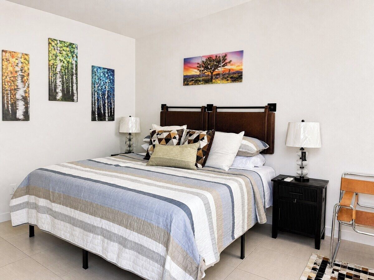 A neatly made bed with a striped bedspread, a wooden headboard, and two bedside tables with lamps.