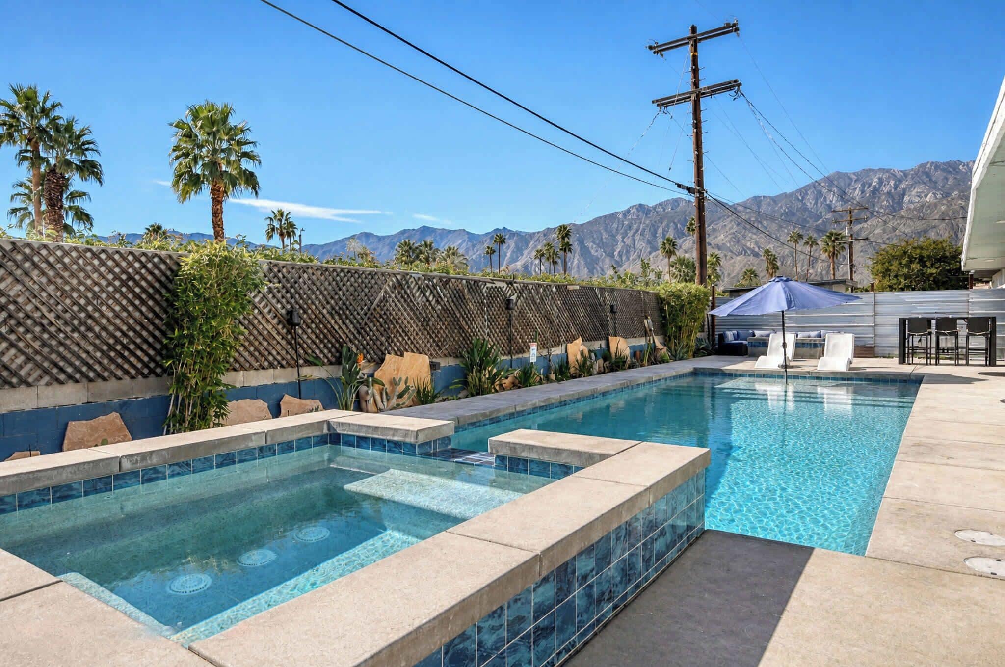 A swimming pool with a view of mountains, a pergola, and a covered seating area.