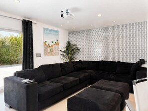 Una sala de estar moderna con un sofá modular, una mesita y un amplio ventanal con cortinas.