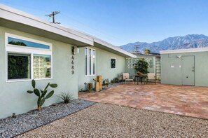 Un edificio residencial con un patio, una planta de cactus y una vista de la montaña al fondo.