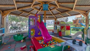 Ein Kinderspielbereich mit Rutsche, Bällebad und verschiedenen Spielgeräten.