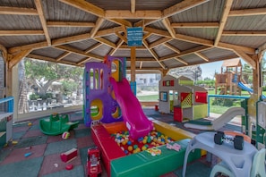 Zona de juegos infantiles con tobogán, piscina de pelotas y diversas estructuras recreativas.
