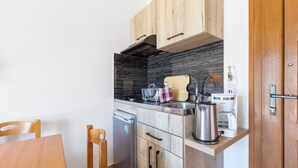 Eine kleine Küche mit Holzschränken, einem eingebauten Herd, einer Kaffeemaschine und einem Wasserkocher.