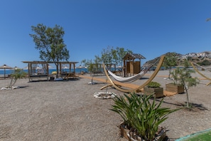 Una zona de playa con hamacas, asientos y plantas en macetas.