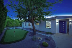 A modern house with a well-maintained lawn, a tree, and a driveway leading to the entrance. - Stylish Palm Springs Retreat | Pool & Spa (Palm Springs)