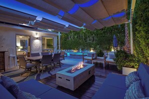 An outdoor patio with a fire pit, seating, and a pool area. - Stylish Palm Springs Retreat | Pool & Spa (Palm Springs)