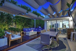 An outdoor patio area with a fire pit, seating, and a view of the interior. - Stylish Palm Springs Retreat | Pool & Spa (Palm Springs)