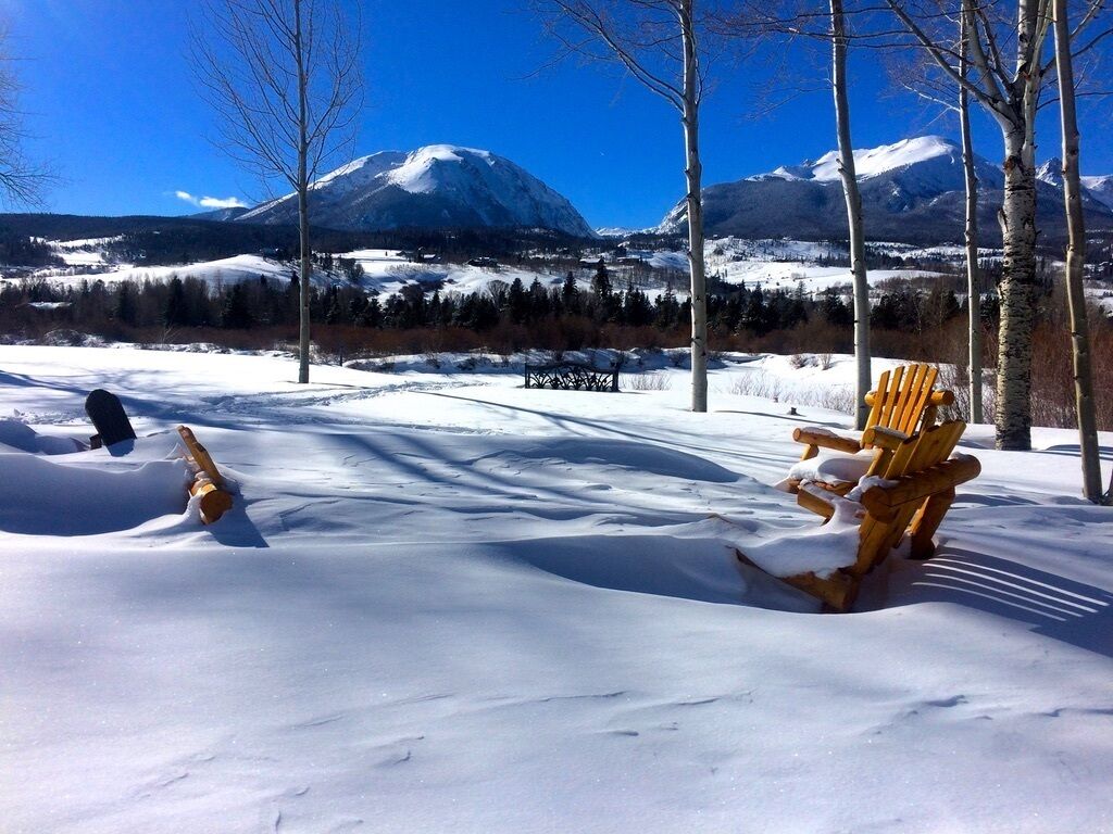 Paisaje nevado con un banco y una estructura de madera, probablemente una mesa de picnic, en primer plano.