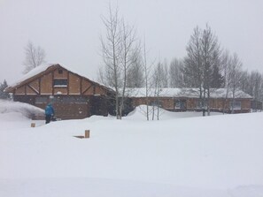 A large wooden building with a snow-covered roof, surrounded by trees and a snowy landscape. - 3-bedroom, 2-bath gated community of Blue River Valley Ranch Lakes (Silverthorne)