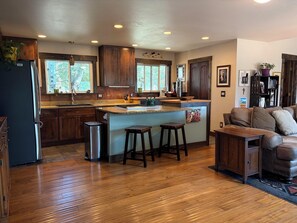 A modern kitchen with wooden cabinets, a stainless steel refrigerator, and a bar area with stools. - 3-bedroom, 2-bath gated community of Blue River Valley Ranch Lakes (Silverthorne)