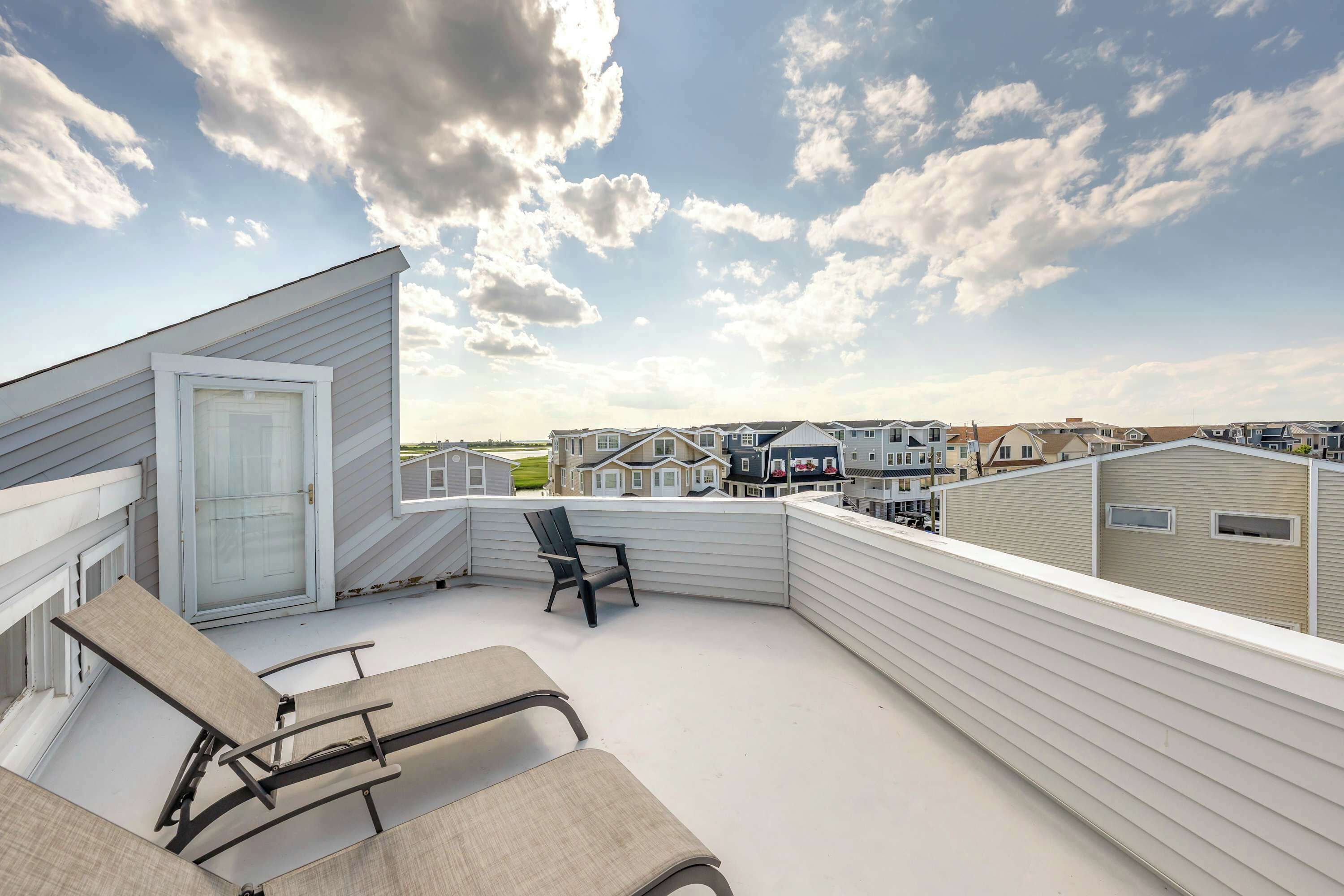 A balcony with a chair and a table, overlooking a row of townhouses.