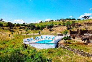 A swimming pool with blue chairs, surrounded by a stone wall and grassy area. - Apartment 'Quarto 4' with Wi-Fi and Air Conditioning (Corte do Pinto)