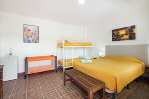 A room with bunk beds, a wooden bench, a desk with a water bottle, and two paintings on the walls.