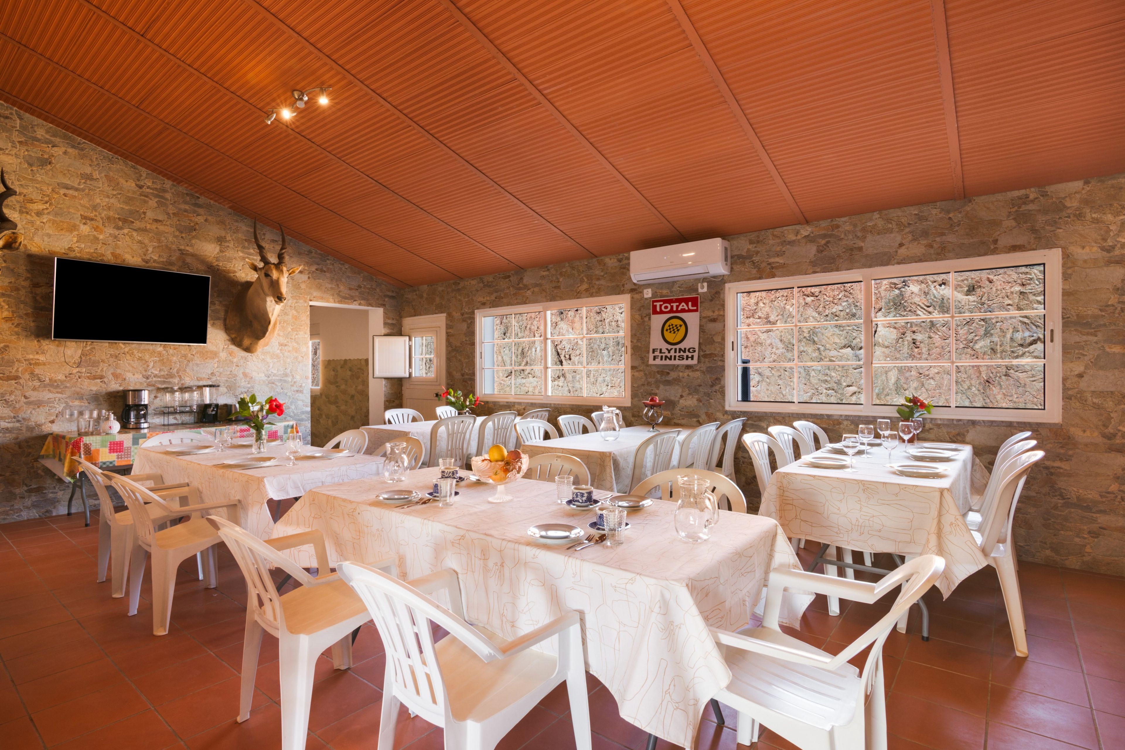 Ein Restaurant mit Steinwänden, Holzbalkendecke und mehreren gedeckten Tischen.