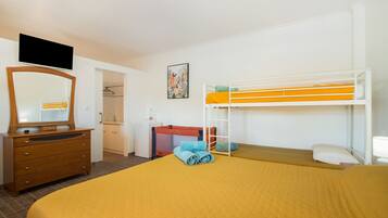 Ein Hotelzimmer mit Etagenbett, Kommode, Spiegel, Fernseher und einer kleinen Küche.