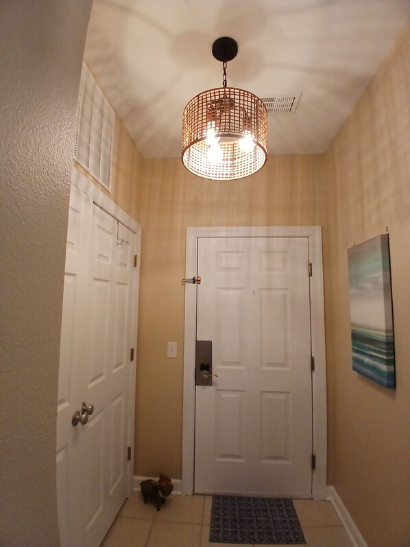 Corredor com porta branca, um cão pequeno e luminária pendente.