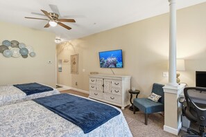 Quarto com duas camas, ventilador de teto, cômoda, televisão e uma cadeira.