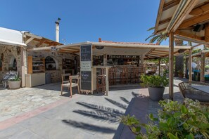 Ein Straßencafé mit Steinböden, Holzmöbeln und einer Bar.