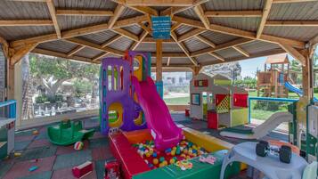 Un espace de jeux pour enfants avec un toboggan, une piscine à balles et diverses structures de jeu.