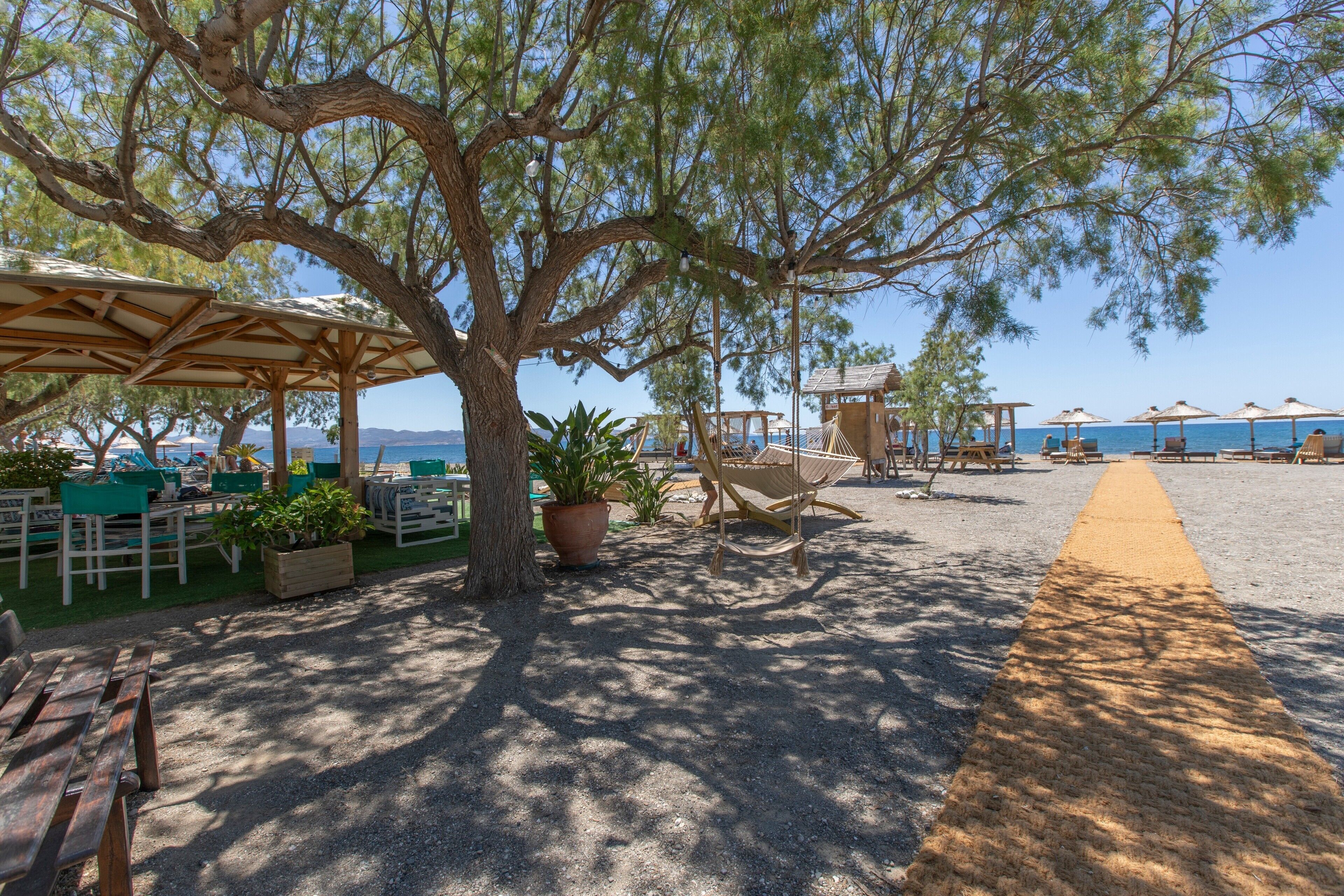 A beachside area with outdoor seating, a hammock, and a view of the sea.