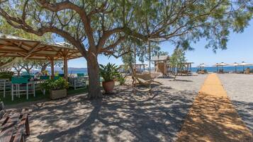 A beachside area with outdoor seating, a hammock, and a view of the sea.