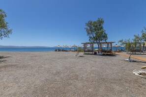 Ein Kiesstrand mit Strandstühlen und einer Holzkonstruktion.