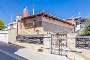 A building with a stone facade, a metal gate, and a red-tiled roof.