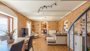 Ein modernes Interieur mit Steinwand, Essbereich mit Fernseher, einer Couch und einer Treppe.