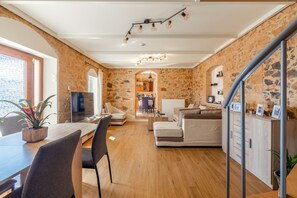 Ein modernes Interieur mit Steinwand, Essbereich mit Fernseher, einer Couch und einer Treppe.