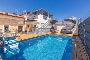 A swimming pool with a wooden deck, a lifebuoy, and a chair.