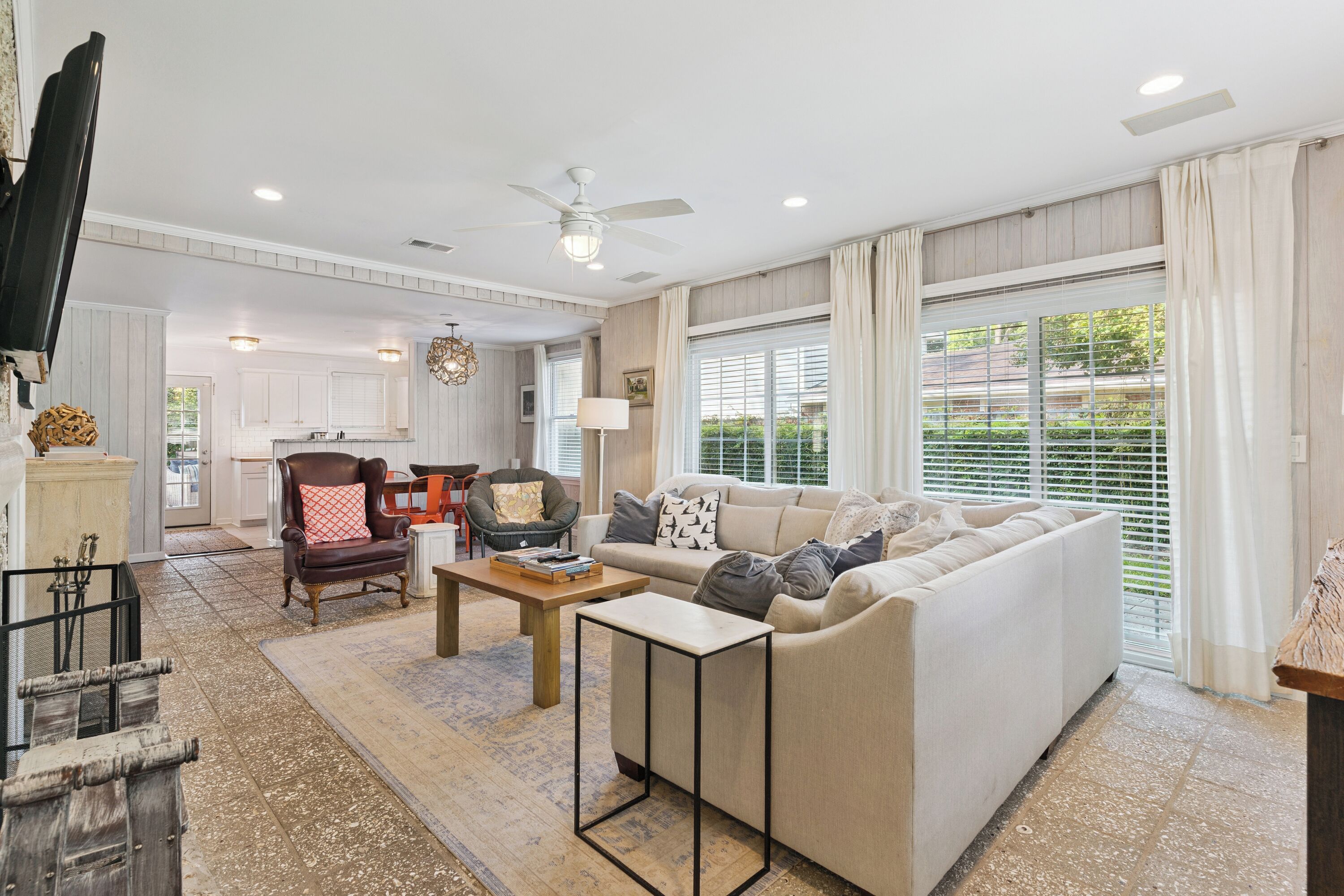 A spacious living room with a large sofa, a coffee table, and a dining area with a chair and table.