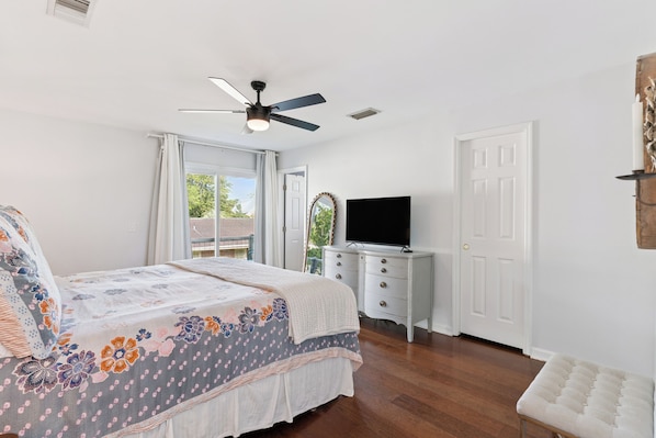 A bedroom with a bed, a dresser, a television, and a ceiling fan.