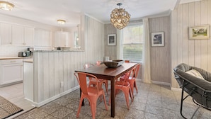 Una cocina con armarios blancos, una isla de madera y una mesa de comedor con sillas naranjas.
