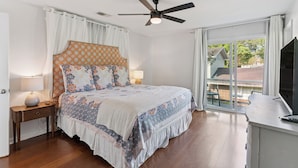 Un dormitorio con cama, lámparas de noche, ventilador de techo y vistas al exterior.
