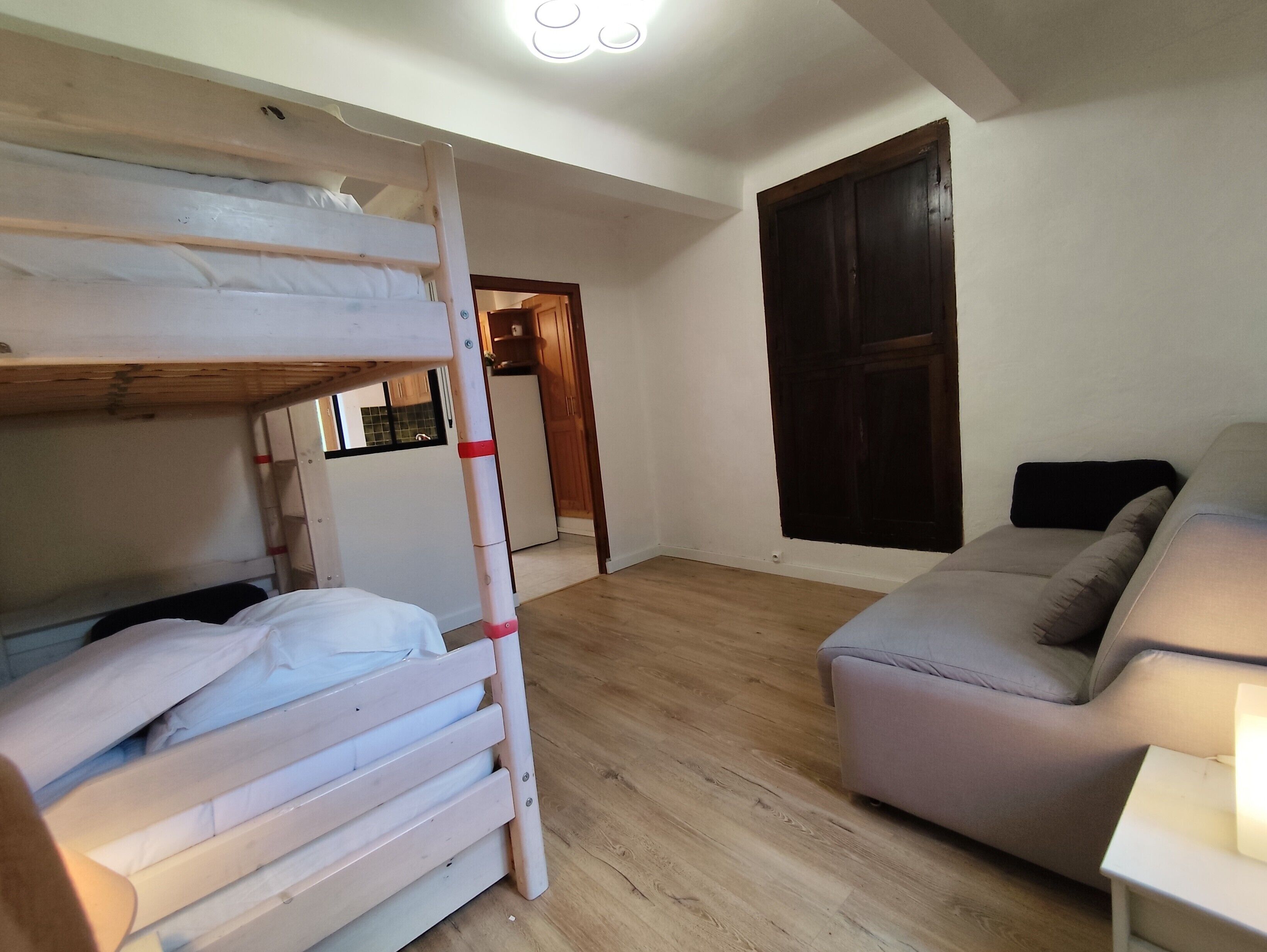 Une pièce avec un lit superposé, un canapé et un plancher en bois.