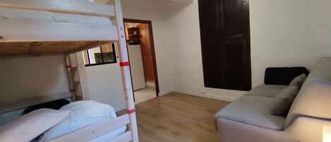 Ein Zimmer mit einem Etagenbett, einer Schlafcouch und Holzboden.
