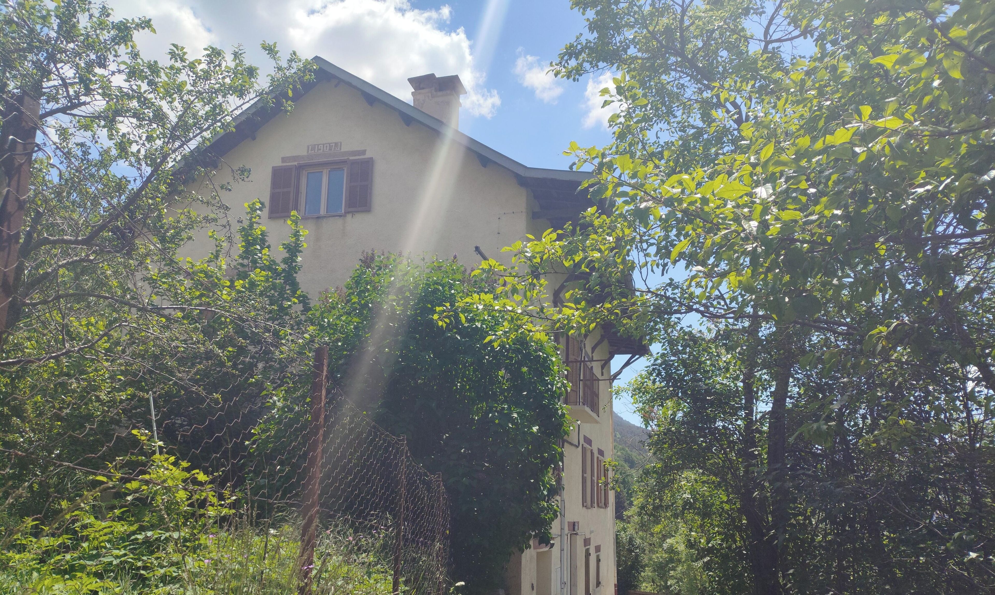 Un bâtiment doté d’une cheminée, d’une fenêtre avec des volets et d’une enseigne au-dessus de la fenêtre.