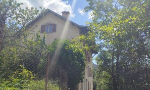 A building with a chimney, a window with shutters, and a sign above the window.