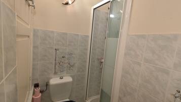 Une salle de bain avec une douche à parois de verre, des toilettes et un porte-serviettes.