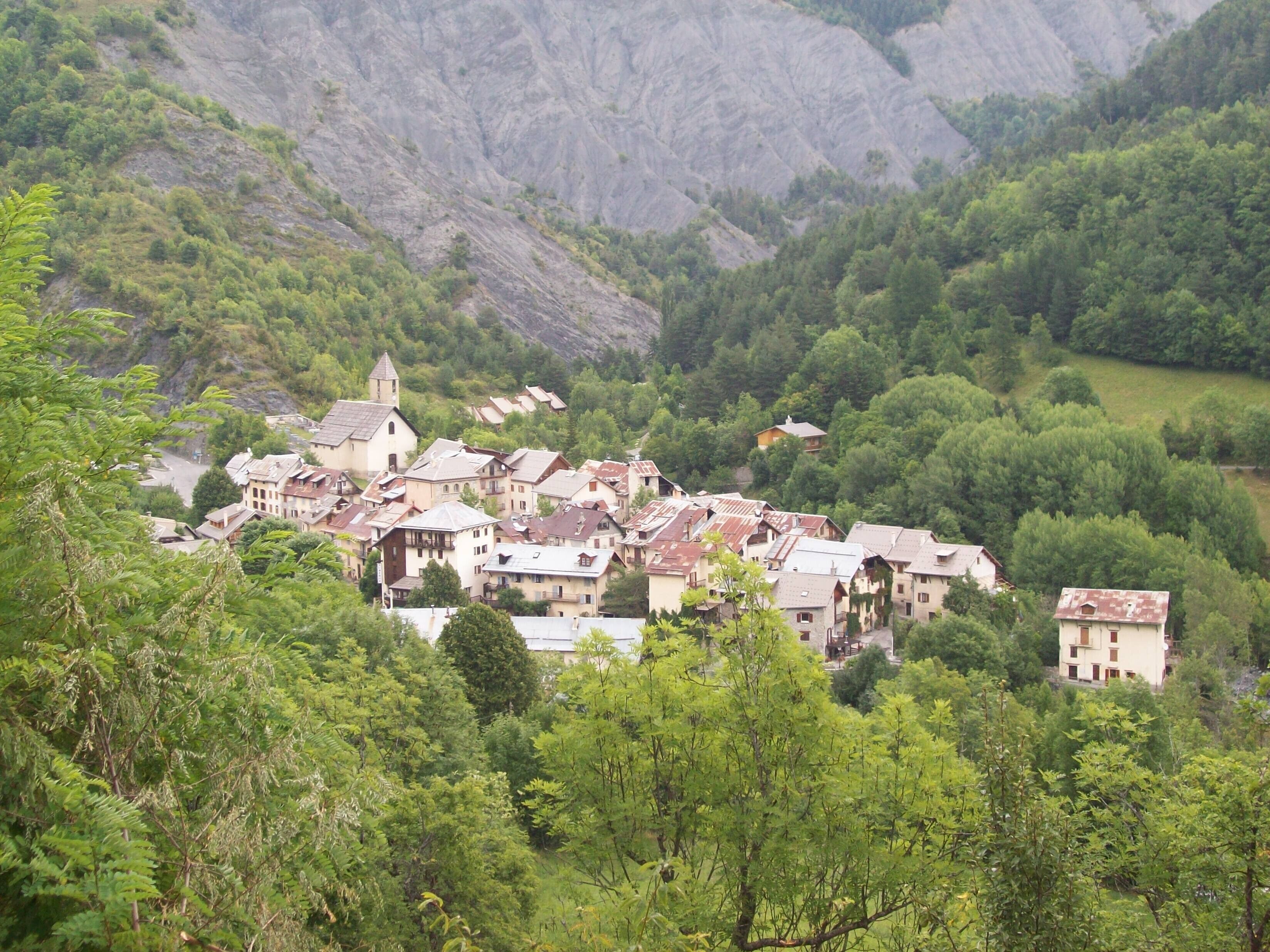 Un pueblo con arquitectura tradicional ubicado en un valle rodeado de colinas boscosas.