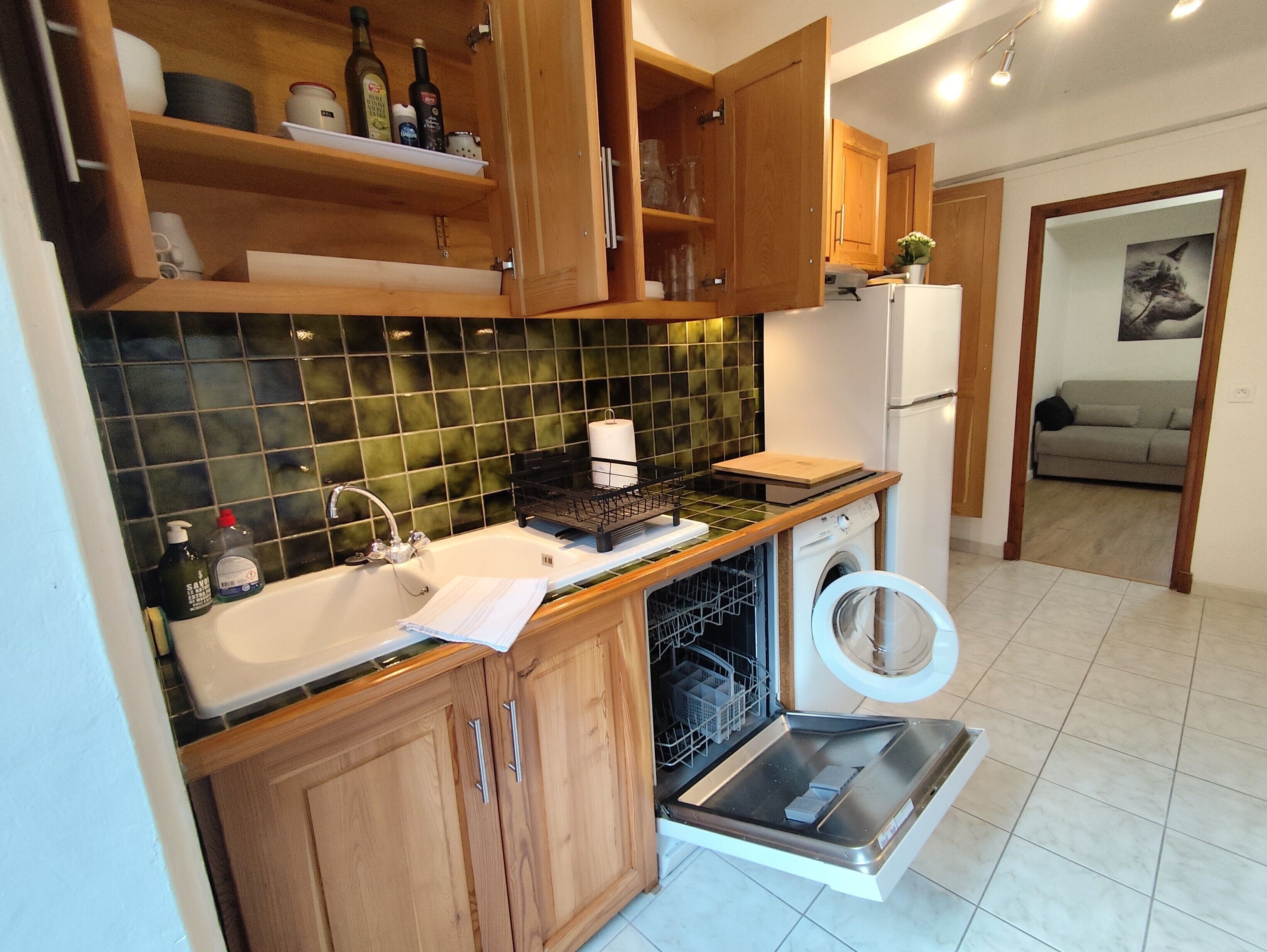 A kitchen with wooden cabinets, a sink, a dishwasher, and a refrigerator.